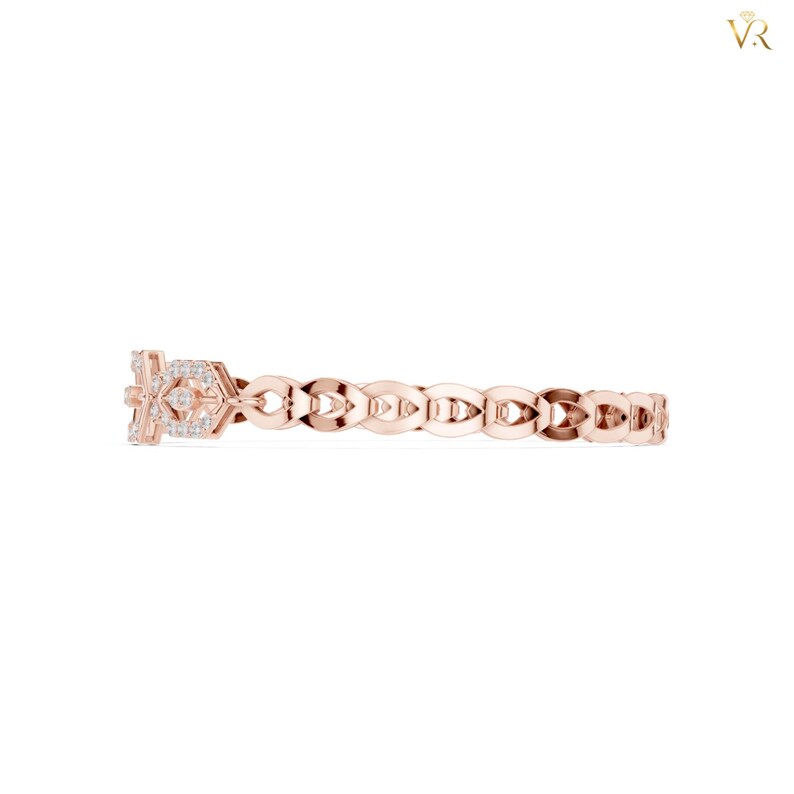 May include: A rose gold ring featuring a repeating openwork leaf-like pattern along the band. The focal point is a rectangular section adorned with small, clear, round-cut stones set in a geometric arrangement, creating a delicate and refined appearance.