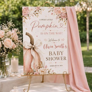 May include: A rectangular baby shower welcome sign featuring a watercolour illustration of a pale pink pumpkin with a white bow, surrounded by blush roses. The text reads A SWEET LITTLE Pumpkin IS ON THE WAY! Welcome to Olivia Smith's BABY SHOWER FEBRUARY 10, 2025.
