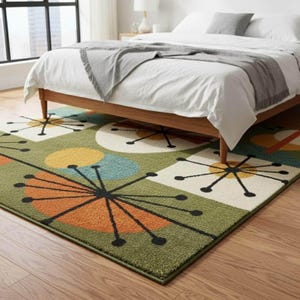 Può includere: Un tappeto rettangolare con sfondo verde e un motivo ripetuto di quadrati e cerchi bianchi contenenti forme a stella nere, insieme ad accenti semicircolari arancioni, gialli e blu, posizionato sotto una struttura letto in legno.