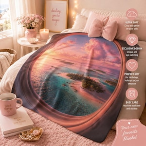 Puede incluir: Una manta suave con un estampado circular de un paisaje de isla tropical al atardecer con nubes rosas y naranjas sobre agua turquesa. La manta está colocada sobre una cama con un cojín rosa en forma de lazo e incluye superposiciones de texto.