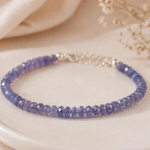 Può includere: Un braccialetto delicato composto da piccole perle di pietre preziose sfaccettate color blu pervinca disposte in un motivo circolare. Il braccialetto presenta un meccanismo di chiusura metallico color argento e una catenella di estensione regolabile.