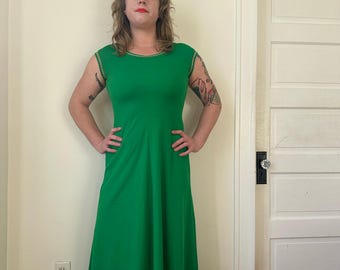 Puede incluir: Un vestido largo verde brillante con mangas cortas y cuello redondo. El vestido tiene un corpiño ajustado y una falda fluida. El cuello y los bordes de las mangas están adornados con costuras doradas. El vestido está hecho de una tela lisa y sólida.