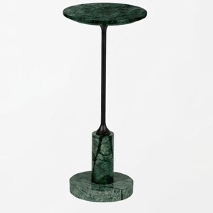 May include: A side table featuring a circular dark green marble top and a matching circular marble base. The two marble components are connected by a slender, matte black metal central stem that rises from a cylindrical marble pedestal.