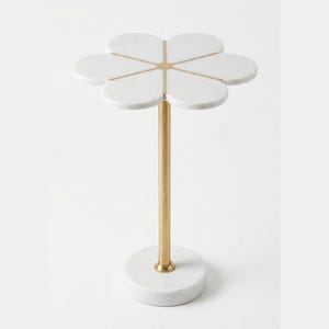 May include: A side table featuring a white marble top shaped like a six-petal flower with gold-toned metal accents between the petals. The table has a slender gold-toned metal central column supported by a circular white marble base.