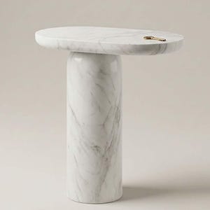 May include: A white marble side table with a smooth oval top and a thick cylindrical base, featuring natural grey veining throughout the stone surface. A single small brass-coloured metal key rests on the flat top of the table.