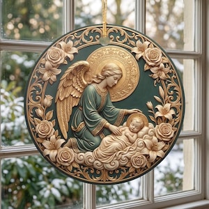 May include: A circular wall hanging featuring a relief carving of an angel with wings reaching toward a baby resting on clouds. The design is accented with gold-toned roses and lilies against a dark green background, suspended by a gold cord.