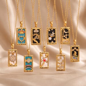 Può includere: Una collezione di nove collane con pendente rettangolare color oro, ognuna caratterizzata da un design unico di carta dei tarocchi con smalto intarsiato, pietre preziose colorate e cristalli trasparenti. Ogni pendente è appeso a una catenina dorata.