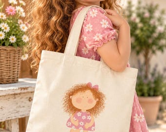 May include: A cream-colored canvas tote bag featuring a centered graphic illustration of a curly-haired character wearing a pink dress with white flowers and a small pink hair bow, matching the style of the bag's simple rectangular design.
