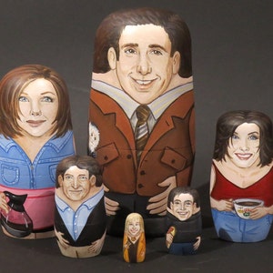 Peut inclure: Ensemble de six poupées russes peintes à la main, représentant les personnages de la série télévisée "Friends". Chaque poupée est ornée d'un portrait détaillé, la plus grande représentant Ross en costume marron. La plus petite est Phoebe.