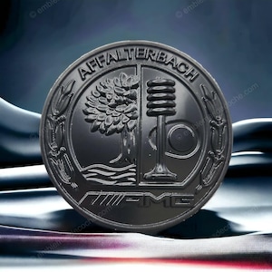 Könnte beinhalten: Ein kreisförmiges schwarzes Emblem mit dem Schriftzug AFFALTERBACH oben und AMG unten. Das mittlere Design ist in zwei Hälften geteilt und zeigt einen Baum auf der linken Seite und ein Ventil auf der rechten Seite, umrahmt von stilisierten Ähren.