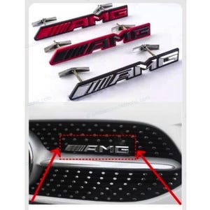 Könnte beinhalten: Drei AMG-Embleme aus Metall mit Befestigungsstiften in den Farben Rot, Schwarz und Silber. Darunter ist ein silbernes AMG-Emblem an einem schwarzen Autokühlergrill mit Punktmuster montiert, hervorgehoben durch ein rotes Rechteck und zwei rote Pfeile.