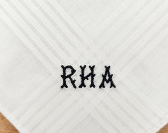 May include: White linen handkerchief with black embroidered initials "RHA".