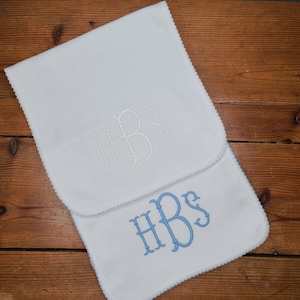 May include: Two white burp cloths with scalloped edges. The top cloth has the monogram "HBS" embroidered in white thread. The bottom cloth has the same monogram embroidered in light blue thread.