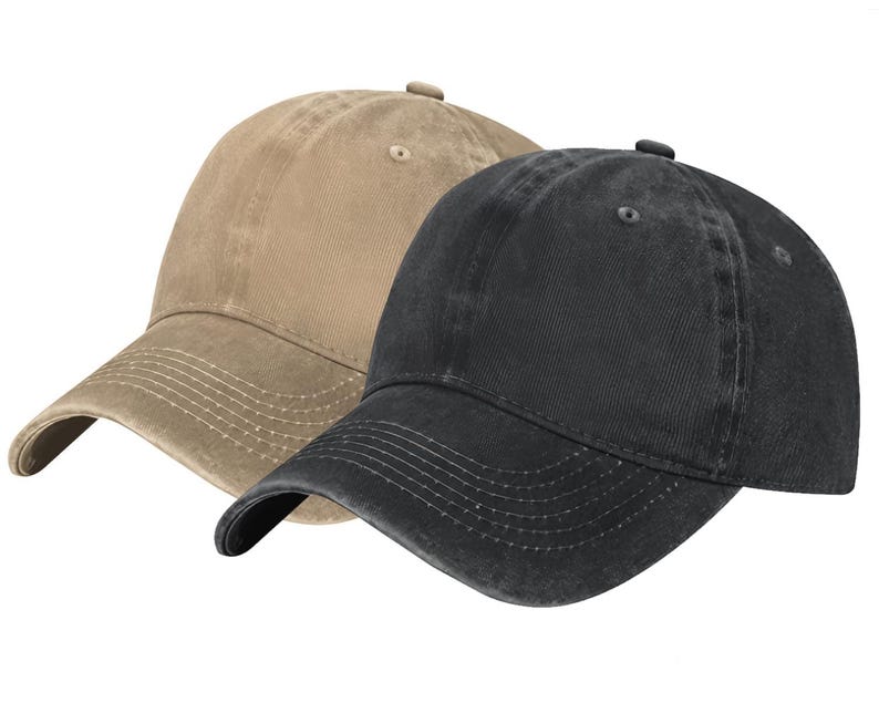 May include: Two baseball caps, one in a tan color and one in a black color. Both caps feature a six-panel construction with a curved brim, stitched detailing on the visor, and a small button at the top center of the crown. The fabric has a washed finish.