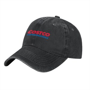 May include: A black baseball cap with a distressed, washed-out finish. The front features the red and blue Costco Wholesale logo embroidered in the center. The cap has a curved brim with visible stitching and a button on the top crown.