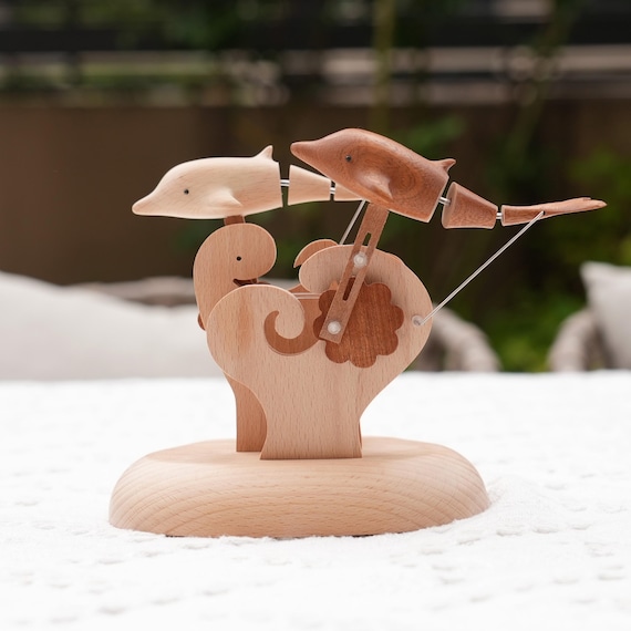 A hand-carved wooden dolphin automaton whose tail and fins actually move in a lifelike swimming motion — mechanical ocean poetry on your shelf.