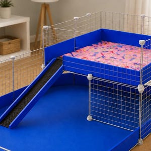 May include: A two-level pet cage featuring a silver wire grid frame with blue plastic base liners. The upper level includes a pink patterned mat and is connected to the lower level by a blue ramp with a black textured surface for traction.