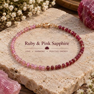 Peut inclure: Un bracelet de perles composé d'un dégradé de saphirs roses et de rubis facettés, alternés avec de petites perles en métal doré. Le bracelet est doté d'un fermoir mousqueton doré et porte l'inscription Ruby & Pink Sapphire LOVE HARMONY POSITIVE ENERGY.