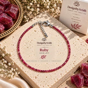 Peut inclure: Un bracelet de cheville en rubis délicat composé de petites perles de pierres précieuses facettées rouge foncé sur un fil fin. Il comprend un fermoir mousqueton argenté et une chaînette réglable. Une carte affiche le texte Ruby ANKLET.