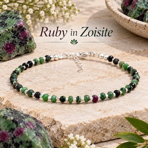 May include: A beaded bracelet featuring faceted ruby in zoisite stones interspersed with small silver-toned metal beads. The bracelet includes a silver-toned metal chain extender and a clasp. The text Ruby in Zoisite is visible above the jewellery.