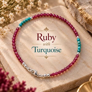 Puede incluir: Una pulsera de cuentas con pequeñas cuentas facetadas de rubí rosa intenso y cuentas de turquesa, acentuada con esferas de plata pulida y un cierre de mosquetón de plata. El texto "Ruby with Turquoise" aparece centrado en la pulsera.