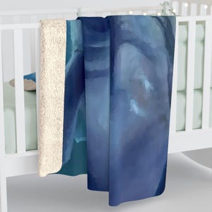 May include: A plush sherpa-lined throw blanket featuring a smooth, abstract watercolour print in various shades of deep navy, royal blue, and light sky blue. The blanket has a thick, textured cream-coloured fleece backing visible along the folded edge.