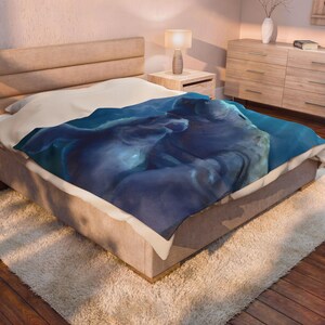 May include: A plush blanket featuring a deep blue and white abstract design draped over a bed. The blanket displays swirling shades of navy, royal blue, and bright white, creating a fluid, cloud-like pattern across the fabric surface.