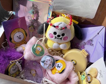 以下が含まれることがあります： ギフトボックスには、黄色のキャラクターのぬいぐるみ、紫色のフェイクファーのポンポン、小さな黄色のコンパクトミラー、ピンクのぬいぐるみヘッドバンド、ビーズのブレスレット、写真ペンダント、ヘアクリップ、キャラクターをテーマにしたステッカーやカードが入っています。