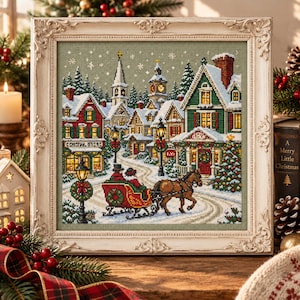 Może przedstawiać: Oprawiony haft krzyżykowy przedstawiający zaśnieżoną zimową wioskę z czerwonymi saniami ciągniętymi przez konia, oświetlonymi latarniami ulicznymi, udekorowanymi domami i wieżą kościelną, w ozdobnej, kremowej, prostokątnej ramie w stylu vintage.