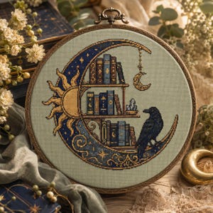 May include: A circular embroidery hoop containing a cross-stitch design on sage green fabric. The pattern features a crescent moon shaped bookshelf filled with blue and gold books, a sun motif, a hanging moon charm, and a black raven perched below.