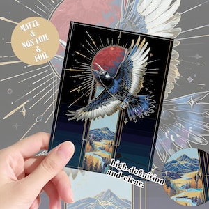Könnte beinhalten: Ein rechteckiger Aufkleber mit einer schwarzen Krähe im Flug vor einem roten Mond und einem dunklen Himmel. Unter dem Vogel befindet sich eine Landschaft mit Bergen, Bäumen und einem Fluss. Der Text lautet Matte & Non Foil & Foil und high-definition and clear.