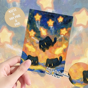 May include: A rectangular art print featuring an oil painting style illustration of three black cats with yellow eyes floating amidst a vibrant orange and blue sky filled with glowing yellow stars. The print includes text stating Matte & Non Foil & Foil.