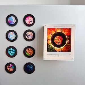 Könnte beinhalten: Acht kreisförmige Magnete mit verschiedenen bunten Illustrationen im Anime-Stil und ein rechteckiger Acrylrahmen mit einem zentralen kreisförmigen Ausschnitt, beleuchtet durch ein warmes Licht, mit dem Text THIS IS THE SHINING STAR IN MY ORDINARY LIFE.