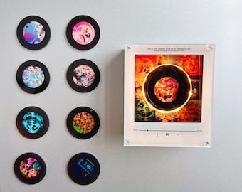 May include: Eight circular magnets featuring various colorful anime-style illustrations and a rectangular acrylic frame with a central circular cutout, illuminated by a warm light, displaying the text THIS IS THE SHINING STAR IN MY ORDINARY LIFE.