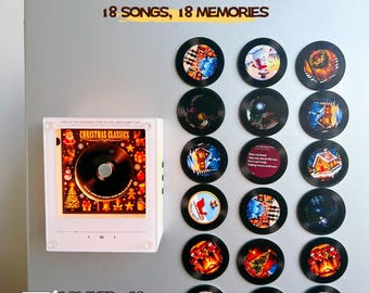 May include: A white square music player featuring a central disc and a display showing Christmas Classics, accompanied by eighteen circular black records with colorful imagery. Text includes Personalized with your own photos and songs, 18 SONGS, 18 MEMORIES, 1 PLAYER + 18 CUSTOM RECORDS, and 18 Photos 18 Songs.
