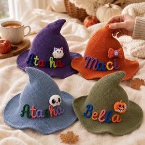 May include: Four knitted witch hats in purple, orange, blue, and olive green. Each hat features a unique embroidered name in colourful yarn and a small decorative applique, including a cat, a bow, a skull, and a jack-o'-lantern pumpkin.