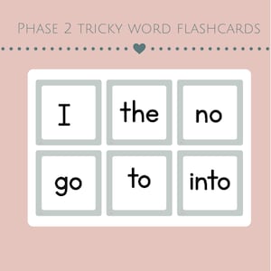 Op de afbeelding: Een set Phase 2 Tricky Word flashcards op een lichtroze achtergrond. De kaarten zijn gerangschikt in een raster van zes witte vierkanten met grijze randen, elk met een zwart woord in kleine letters: I, the, no, go, to, into. De tekst Phase 2 Tricky Word Flashcards staat bovenaan.