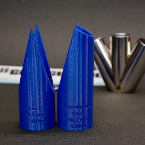 May include: Two blue 3D-printed cylindrical tools with angled tops. Each tool features embossed text reading 3 in 1, 48.3 mm, and 1.90 in. A metallic three-way pipe connector is visible in the background, along with a partially obscured white label.