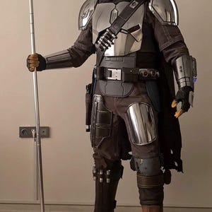 Puede incluir: Un traje de armadura completo en color plata y gris oscuro que incluye un casco met&aacute;lico con visor en forma de T, hombreras, peto, guanteletes y placas para las piernas. El conjunto cuenta con una capa oscura y una lanza larga y delgada.
