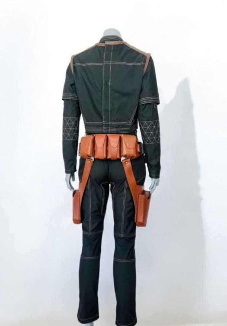 Pu&ograve; includere: Una giacca nera a maniche lunghe e pantaloni abbinati con cuciture bianche a contrasto e motivi geometrici sulle maniche. Una cintura multiuso in pelle color cuoio con diverse tasche e due fondine da coscia &egrave; indossata in vita.