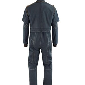 Puede incluir: Un mono gris oscuro con cuello alto, mangas cortas con ribete marr&oacute;n y una cremallera central en la espalda. La prenda incluye costuras blancas en contraste, patrones geom&eacute;tricos en las mangas y pu&ntilde;os de canal&eacute; en color marr&oacute;n.