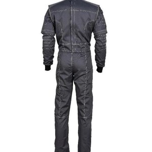 May include: A dark gray racing suit featuring long sleeves with black ribbed cuffs and prominent white contrast stitching throughout the garment. The one-piece coverall design includes a high collar and vertical seam detailing along the back.