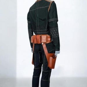 Pu&ograve; includere: Una giacca e pantaloni neri con cuciture bianche a contrasto e un motivo geometrico sulle maniche. Una cintura multiuso in pelle color cuoio con diverse tasche e una fondina &egrave; indossata in vita sopra l'abbigliamento nero.