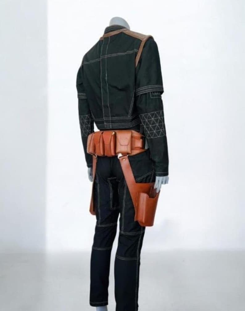 Pu&ograve; includere: Una giacca e pantaloni neri con cuciture bianche a contrasto e un motivo geometrico sulle maniche. Una cintura multiuso in pelle color cuoio con diverse tasche e una fondina &egrave; indossata in vita sopra l'abbigliamento nero.