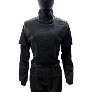 May include: A black long-sleeved top with a high collar and a structured bodice featuring layered shoulder panels, paired with matching black trousers that have prominent white contrast stitching along the legs and a belt loop waistband.