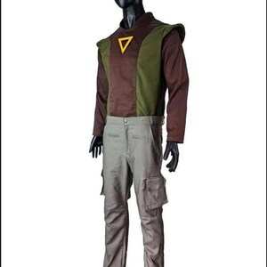 May include: A long-sleeved shirt featuring a brown and olive green color-blocked design with a yellow triangle emblem on the chest, paired with light gray cargo pants that include side pockets, displayed on a black mannequin against a white background.