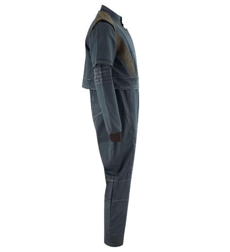 Puede incluir: Un mono de color gris oscuro con cuello alto, mangas largas con pu&ntilde;os marrones y un panel texturizado marr&oacute;n en la parte superior del pecho. La prenda presenta detalles de costuras blancas visibles a lo largo de las costuras, los hombros y las piernas.
