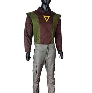 May include: A long-sleeved shirt featuring a brown center panel and olive green side panels with a yellow triangle emblem on the chest, paired with light gray cargo pants. The outfit is displayed on a black mannequin against a white background.