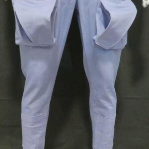 May include: Light blue cargo pants featuring two large, prominent patch pockets on the front of the thighs. The pants have a straight-leg cut with reinforced panels at the lower shins and are finished with cuffed hems at the bottom of each leg.