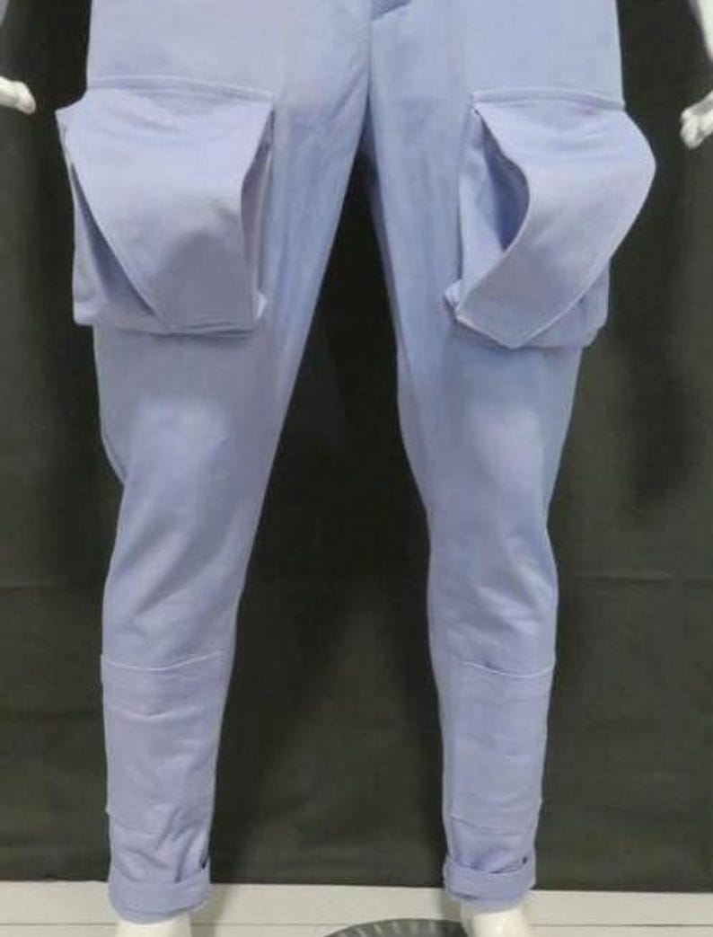 May include: Light blue cargo pants featuring two large, prominent patch pockets on the front of the thighs. The pants have a straight-leg cut with reinforced panels at the lower shins and are finished with cuffed hems at the bottom of each leg.
